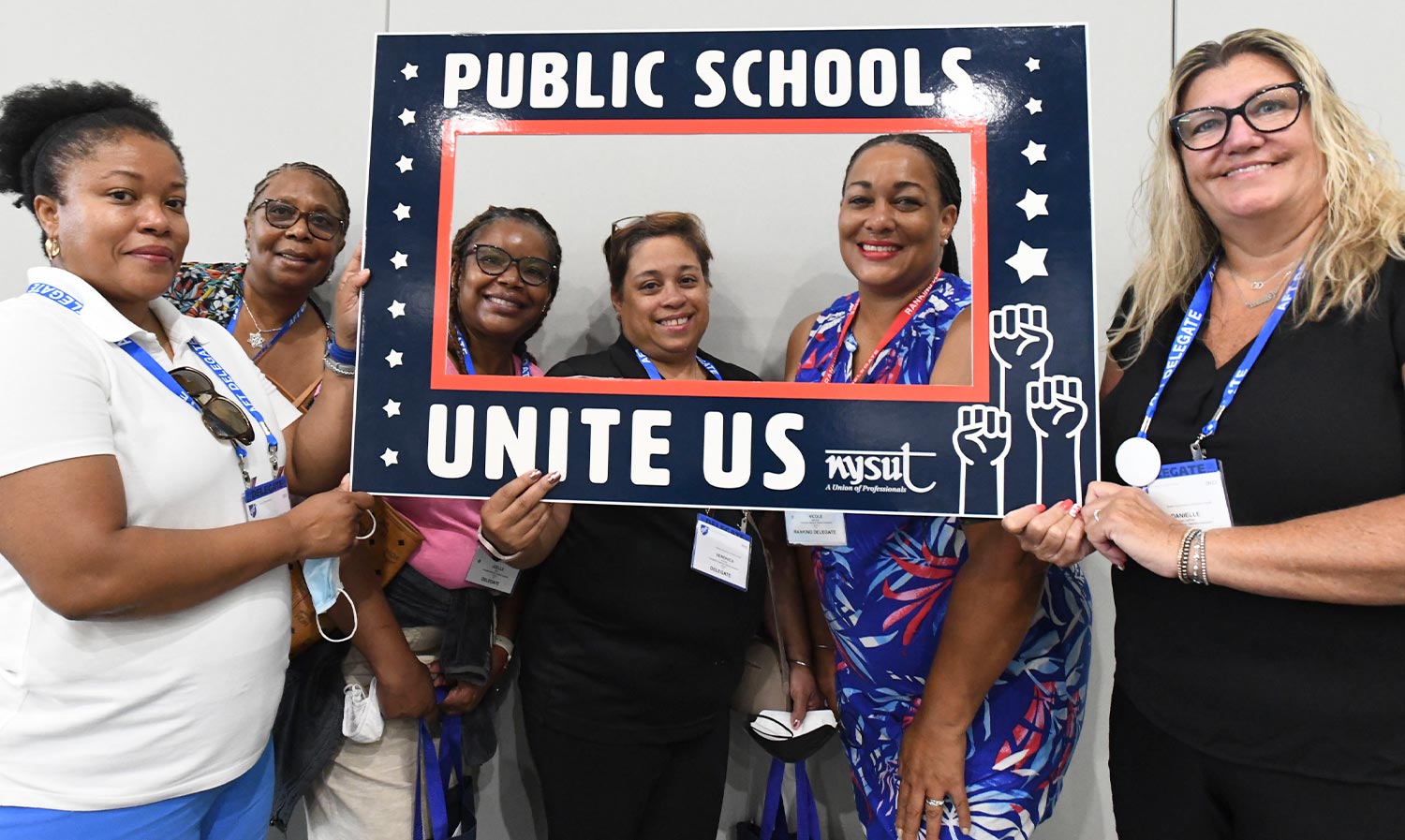 women at the AFT Convention take a group photo holding a "Public Schools Unite Us" graphic frame