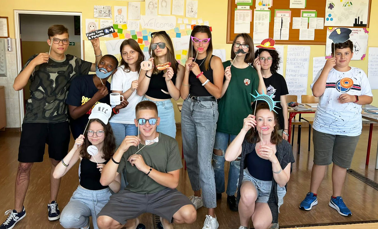 Yonkers Federation of Teachers member Shai Stephenson and her students smile for the camera with their New York-themed props at a summer camp for Ukrainian and Polish students in Cieszanów, Poland.