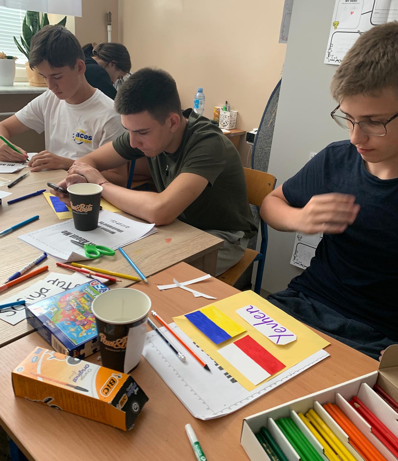 Students in Syracuse TA member Jean-Pierre Rosas’s group decorate graduation caps with flags representing the nations of students and camp counselors at a summer camp for Ukrainian and Polish students in Cieszanów, Poland.