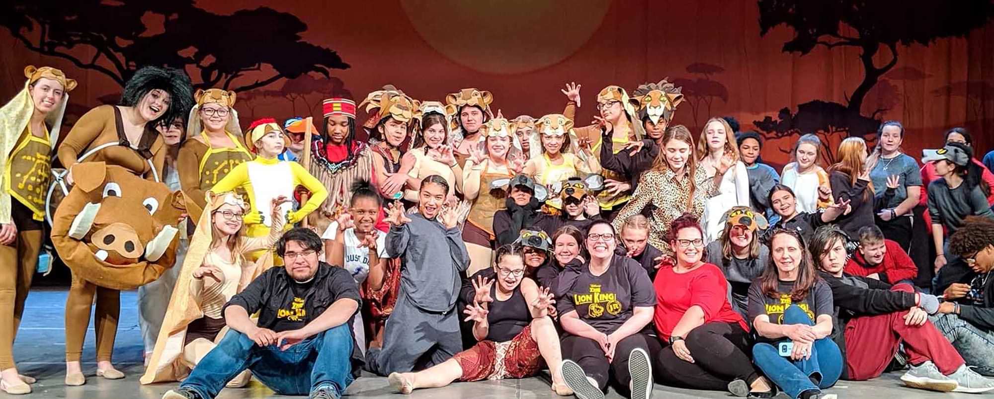 students in the Lion King Jr. play on stage for a cast and crew group photo