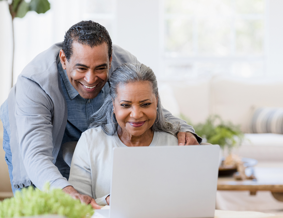 man smiling over the shoulder of a woman on a laptop