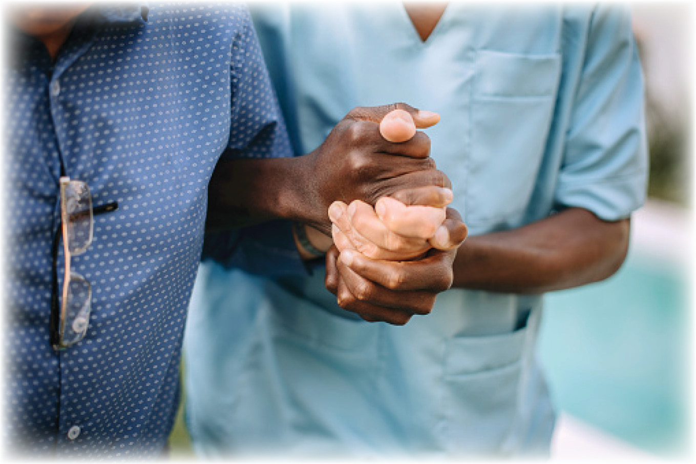 someone in scrubs assisting an elderly man walk with a firm grip on his hand