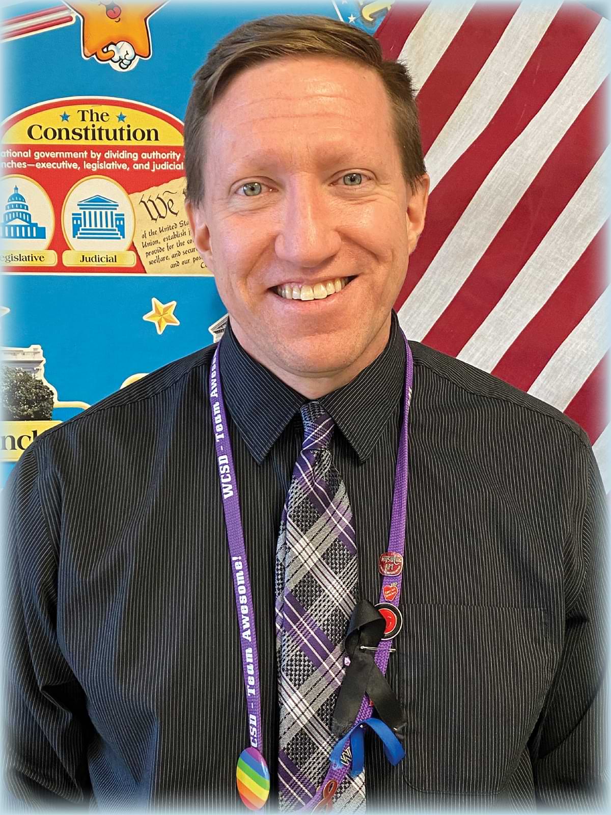lawyer and social studies teacher Kevin Todd photographed smiling in front of a school graphic about the Constitution