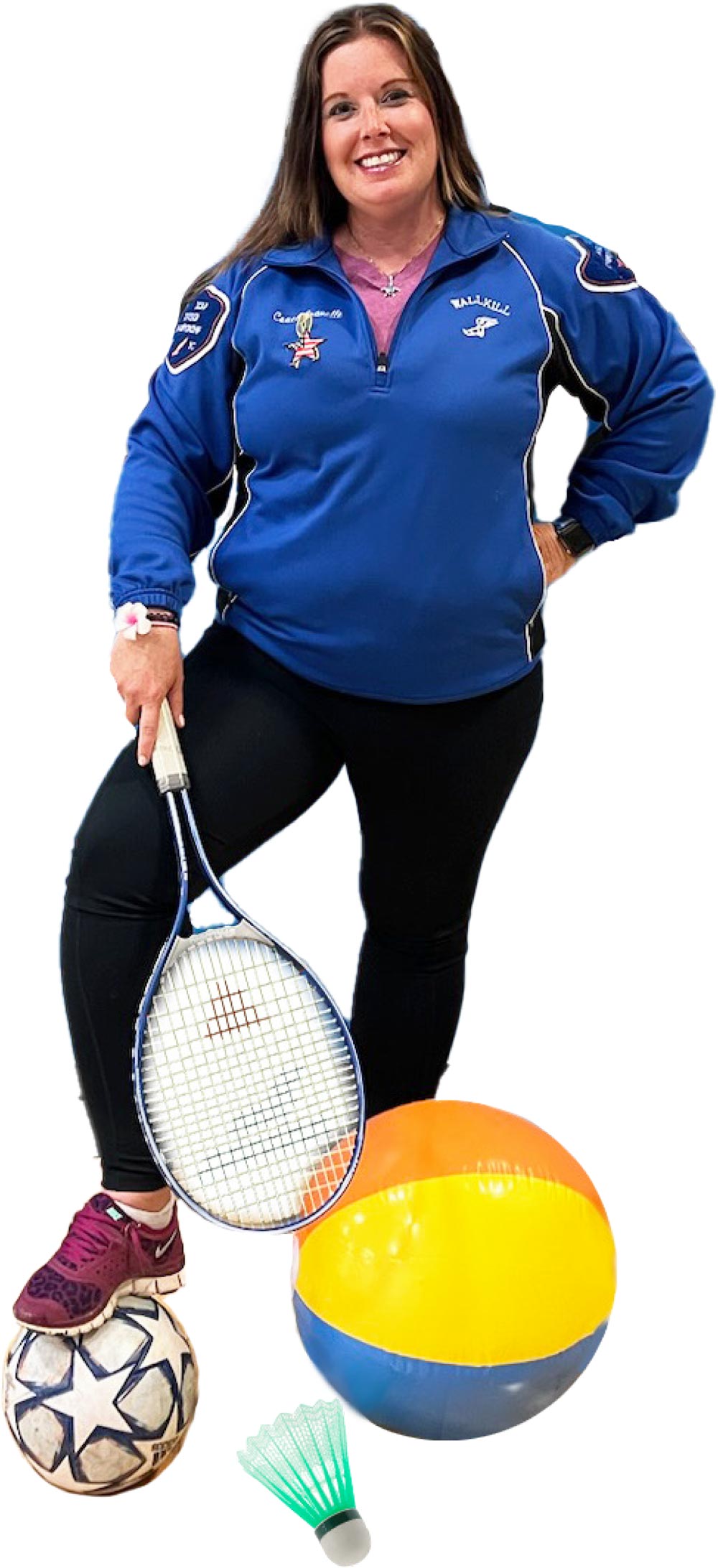 Jennifer Gravelle smiling in a blue/white/black Wallkill custom sport jacket holding a blue/white tennis racket with a soccer ball, a beach ball and an enlarged shuttlecock at her feet