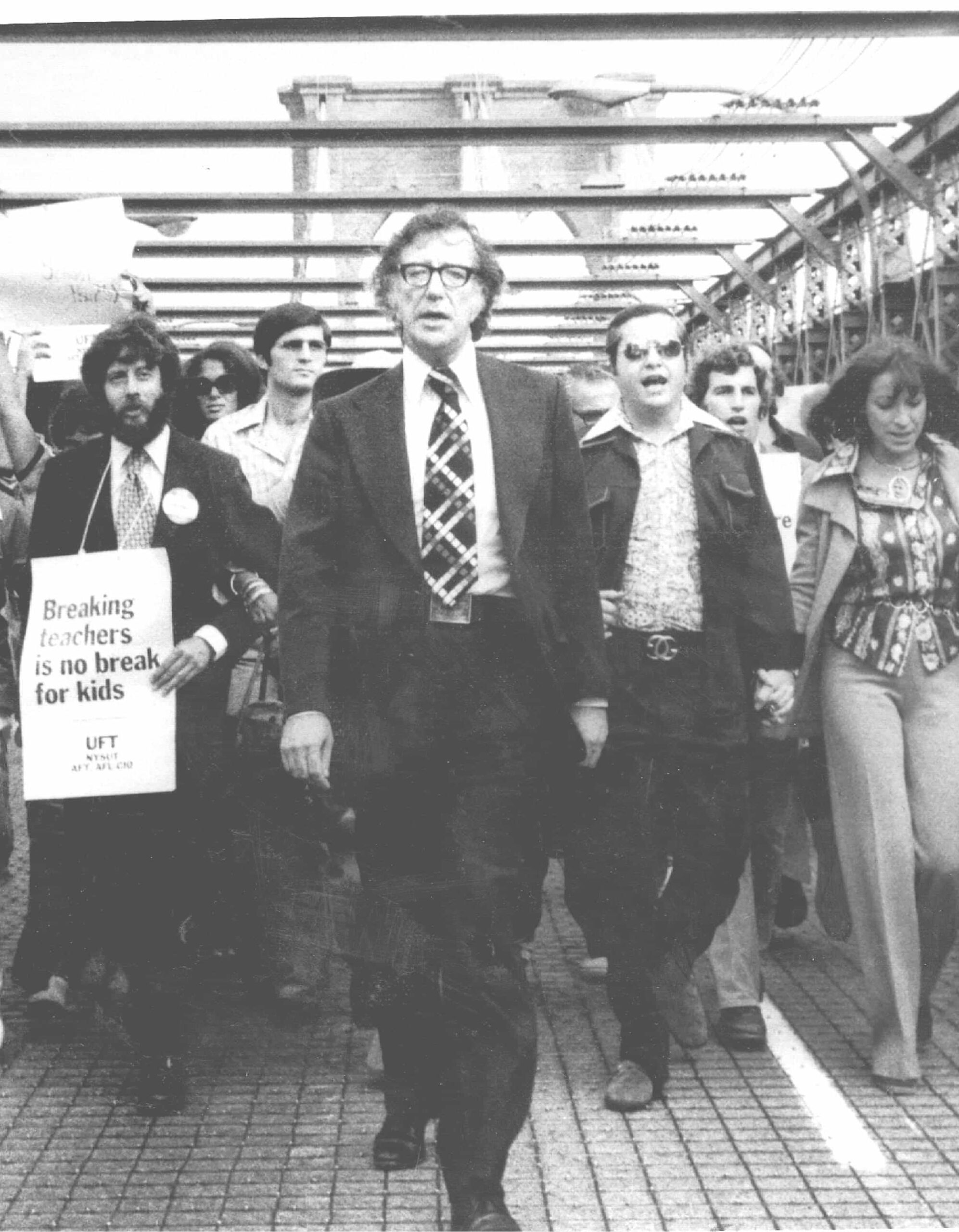 black and white photo of United Federation of Teachers President Al Shanker leading 40,000 teachers and paraprofessionals across the Brooklyn Bridge in 1975 during a demonstrating solidarity in the fight for better classroom conditions