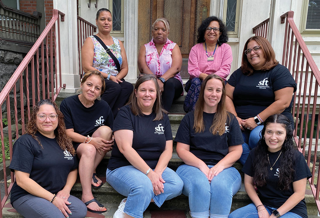 Members of the Schenectady Federation of Teachers Paraprofessional Unit sitting on front steps of a house