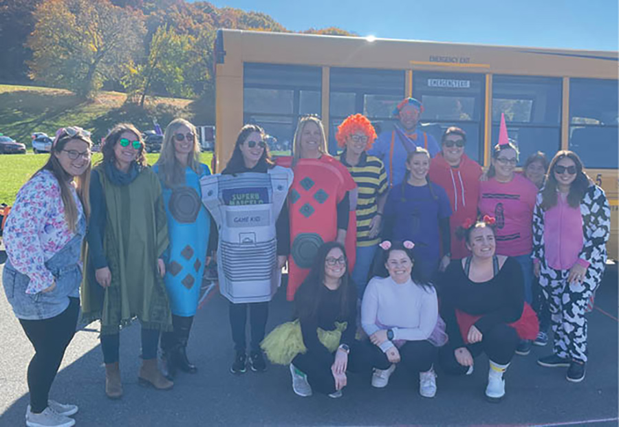 Lansingburgh Teachers Association group dressed in Halloween costumes smiling in front of a school bus