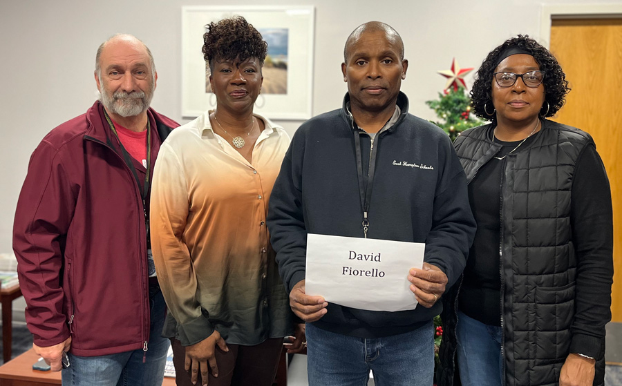 group photo of East Hamptons negotiations team members from left, East Hampton negotiations team members Michael Castello, Amanda Hayes, President Dexter Grady and Samone Johnson; President Dexter Grady holds up a piece of paper that reads: David Fiorello