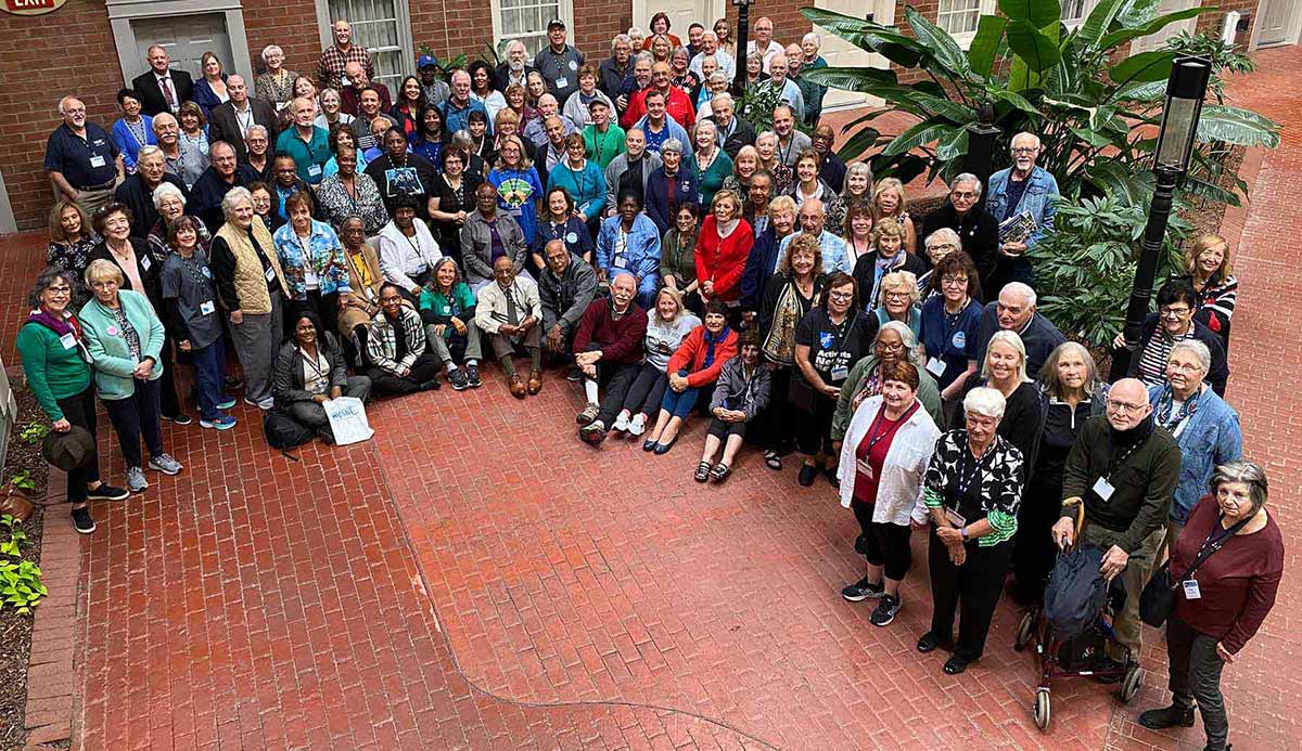Large group of retirees in a courtyard smiling for group photo