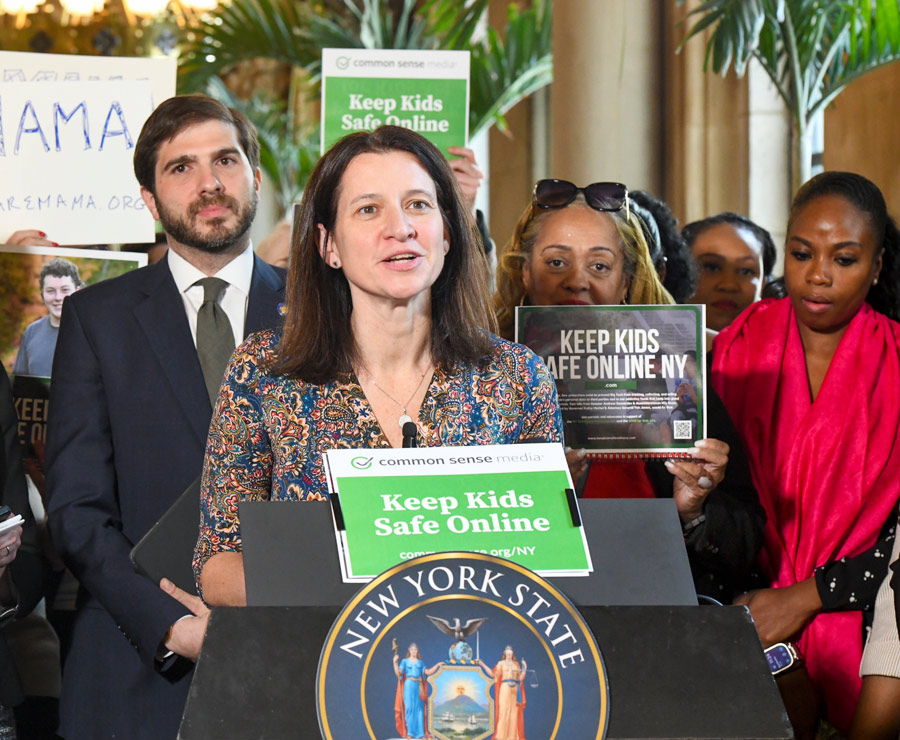 NYSUT President Melinda Person speaking at podium while surrounded by signs discussing online safety for kids