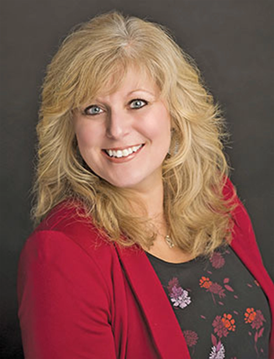 headshot of Lori Atkinson, a woman with shoulder length wavy blonde hair wearing a bright pink blazer and a grey floral blouse