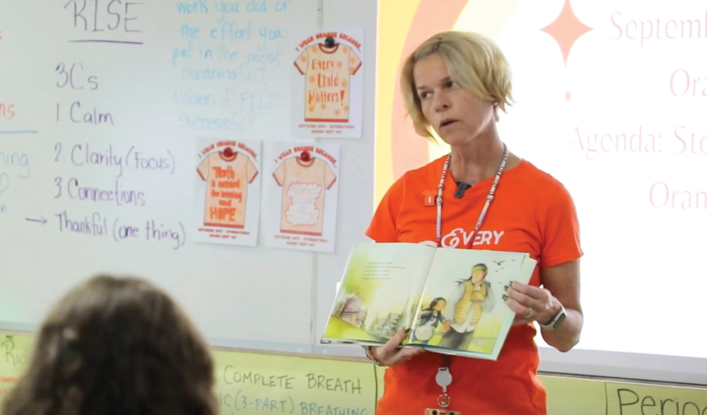 Darla Schultz-Bubar reading a book to her students from the front of the classroom