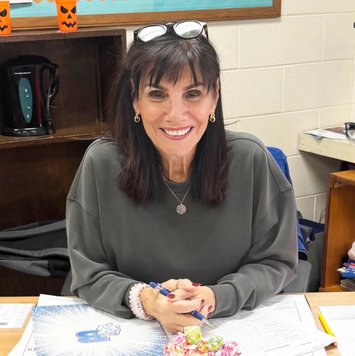 Diane Frascone pictured smiling while sitting at a desk in a classroom