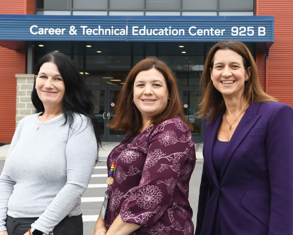 President Melinda Person, Rebecca Breeyear and Katie DiPierro standing together in front of the Career & Technical Education Center 925 B building