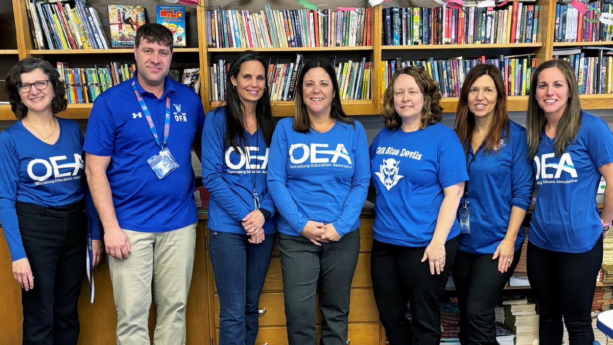 group photo of Ogdensburg Education Association members in front of bookshelf