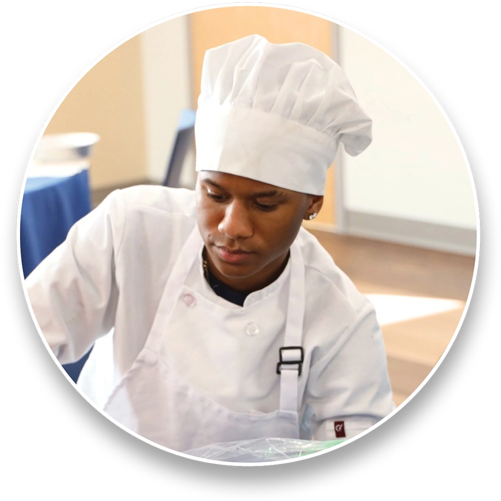 Person in a white chef's uniform and hat working.
