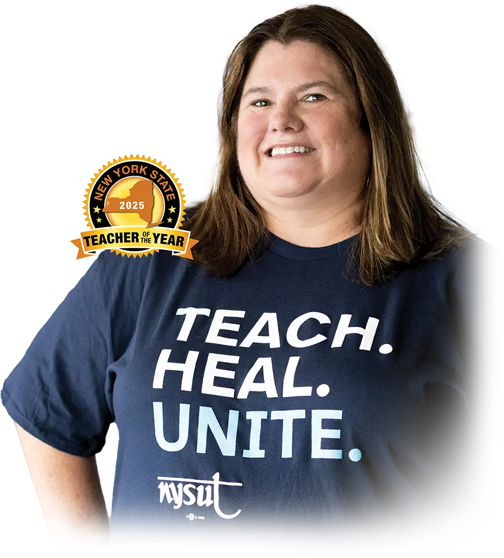 A smiling woman with shoulder-length brown hair stands against a light gray background. She is wearing a dark blue t-shirt with the words "TEACH. HEAL. UNITE." in large white capital letters and a small white "nysut" logo below. A circular gold seal with black text that reads "NEW YORK STATE TEACHER OF THE YEAR 2025" is partially visible in the upper left corner of the image, overlapping her shoulder.