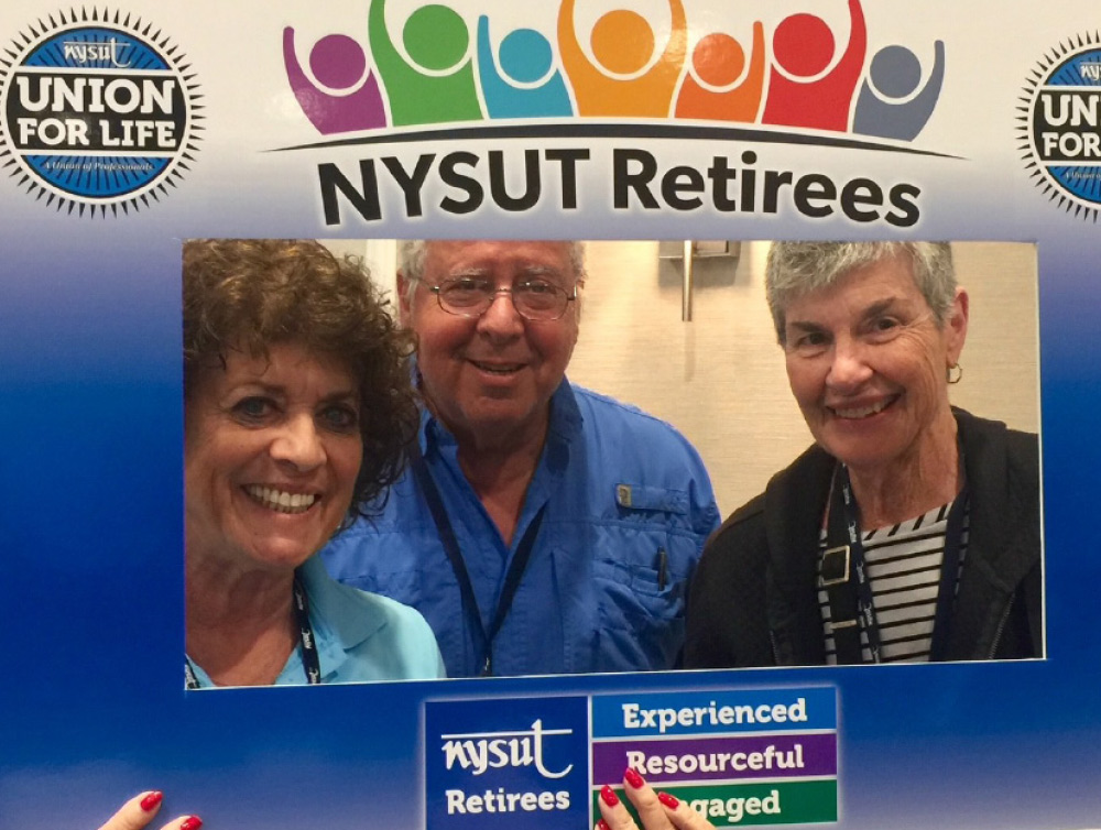 a man and two women holding NYSUT retirees photo frame