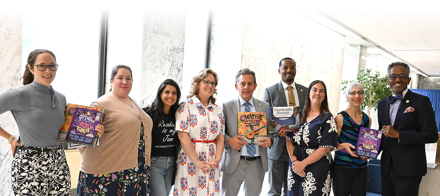 Group of librarians and educators holding diverse children's books, advocating for inclusive literature in schools.