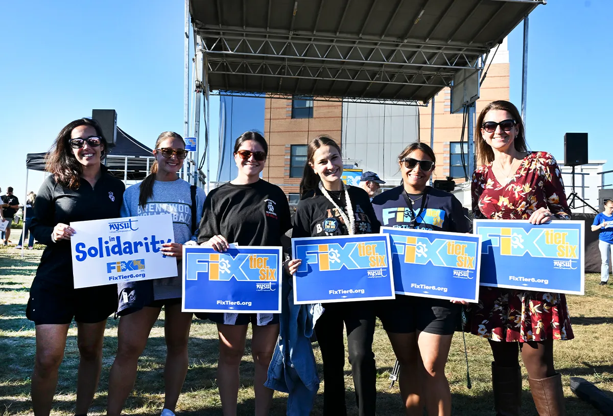 NYSUT members holding "Fix Tier Six" campaign signs at an outdoor rally or union event