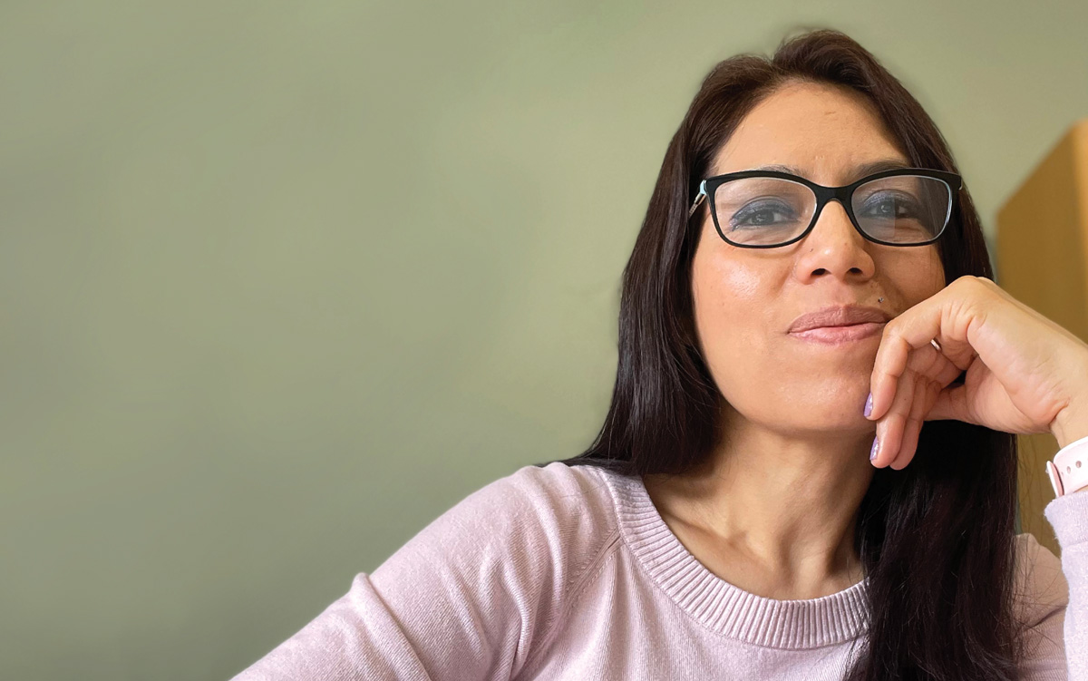 Person with glasses resting their chin on their hand indoors.