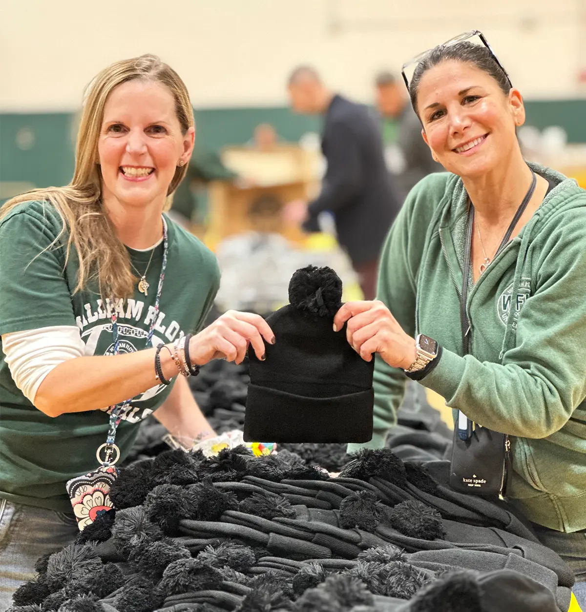 Kate Devenney and Stacy Redmond holding up a knitted beanie
