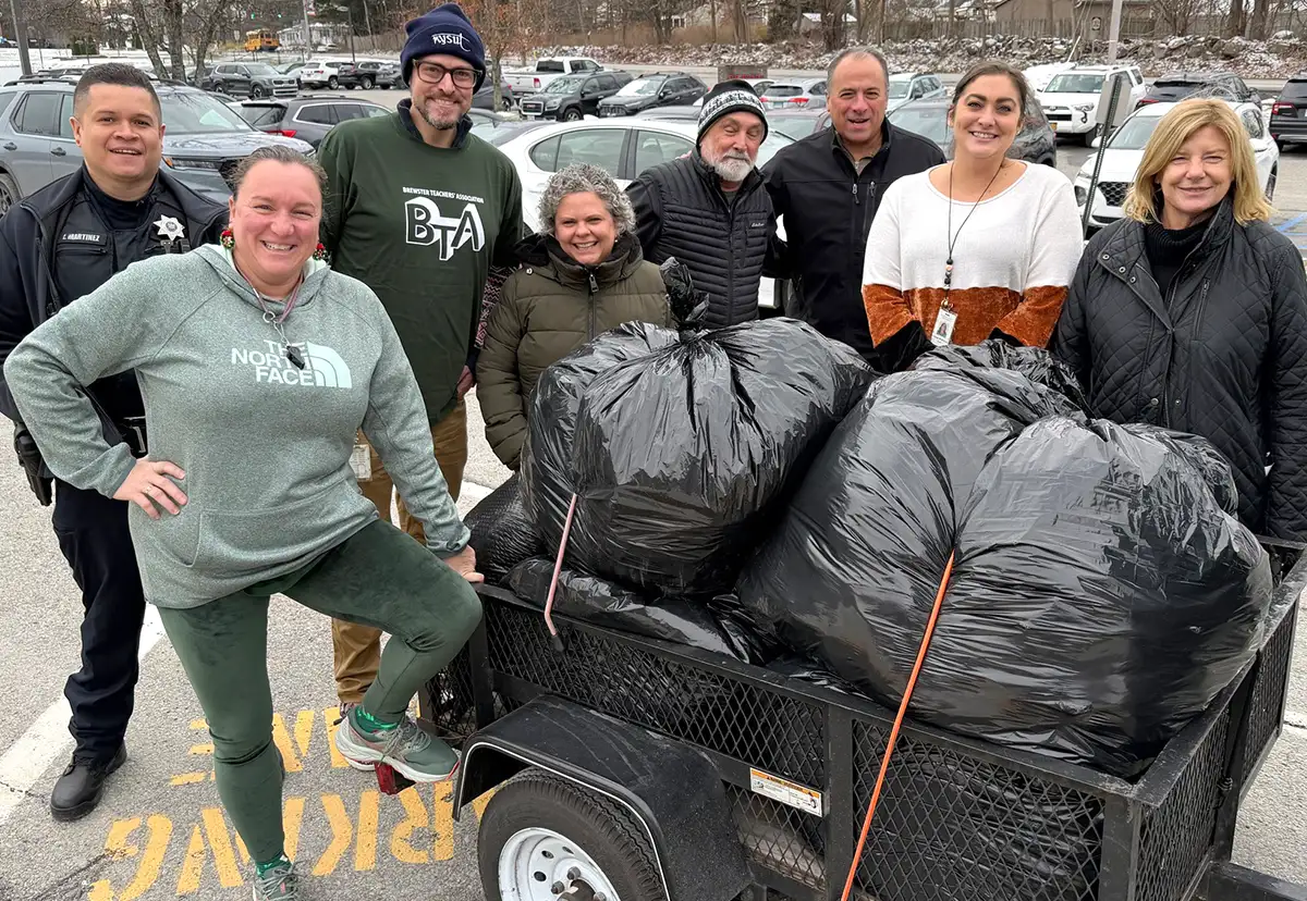 NYSUT local union members and community partners working together to collect and transport large bags of donated goods during a local service project.