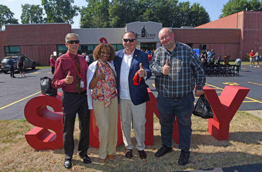 local, state and union leaders posing in front of SUNY letter sign