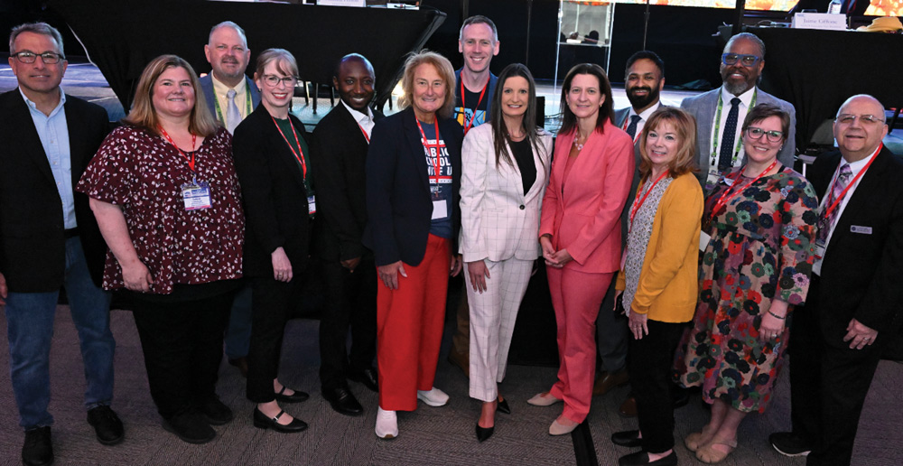 A diverse group of professionally dressed conference delegates and presenters posing together for a group photo.