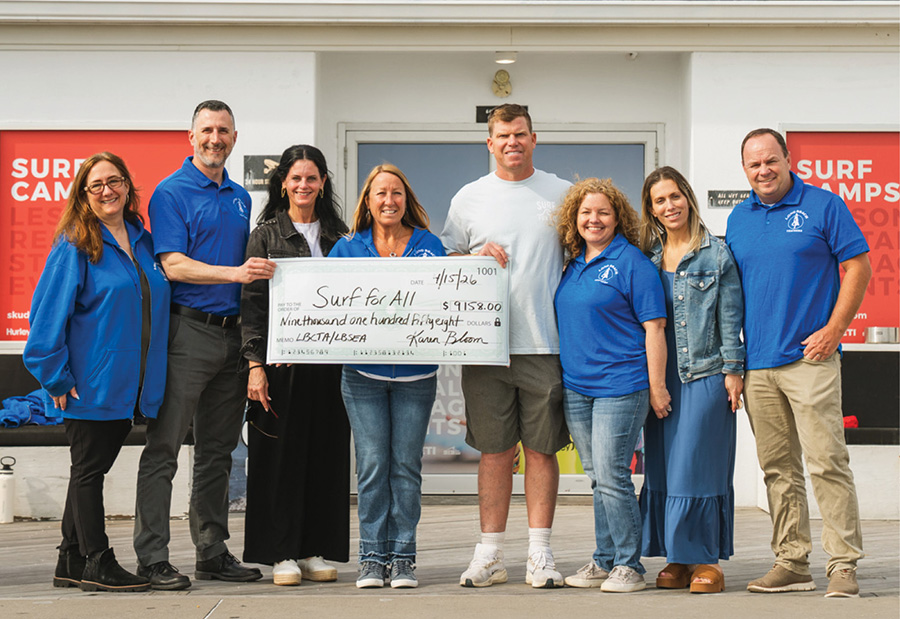 Group of representatives standing outdoors holding a large donation check for "Surf for All."